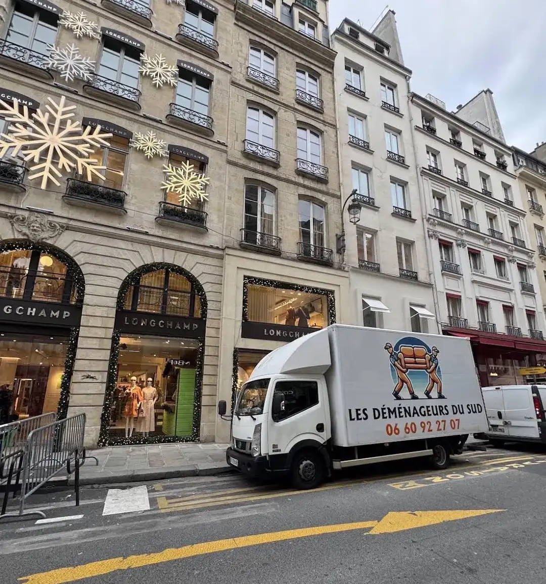 Un camion des Déménageurs Du Sud stationné dans une rue parisienne devant une boutique, pendant une prestation de déménagement